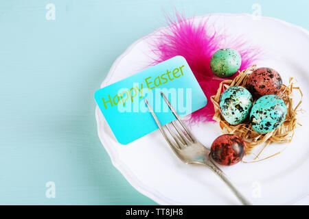Easter table setting with card and Easter eggs on wooden background Stock Photo