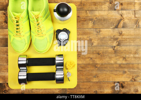 Shoes and sports equipment on mat on wooden floor, top view Stock Photo