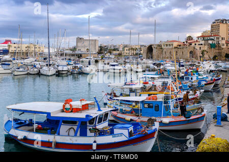 Heraklion, Crete Island / Greece. Traditional colorful fishing boats docked at the old Venetian port in Heraklion city at sunset time Stock Photo