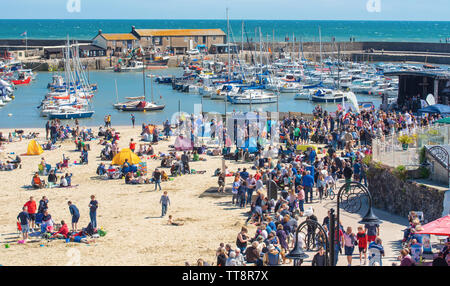 Lyme Regis, Dorset, UK. 15th June 2019. UK Weather: Crowds of musicians and visitors flock to the beach enjoy an afternoon of music as the annual Guitars on the Beach event gets underway on the beach at  Lyme Regis on a glorious afternoon of warm sunshine and bright blue skies. The crowd is the star of the show as guitarists of all ages and abilities gather together on the beach perform together as 'Britain’s biggest band'. People enjoy the laid back festival atmosphere before they perform this year's chosen song “On the Beach”.  Credit: Celia McMahon/Alamy Live News. Stock Photo