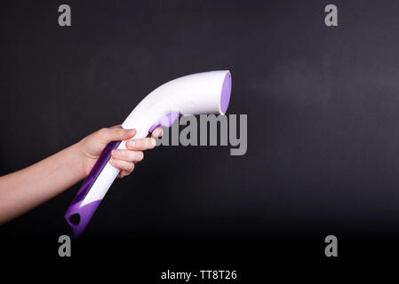 Steamer for clothes in women hand isolated on black Stock Photo