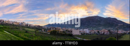 Archanes, Crete Island / Greece. Panoramic view of Archanes town at sunset time. Sun has just went down behind Juktas mountain giving to the cloudy sk Stock Photo