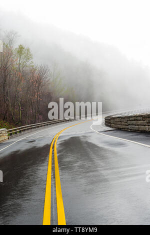 Horizontal shot of a wet curving Smoky Mountain road disappearing into fog with copy space. Stock Photo