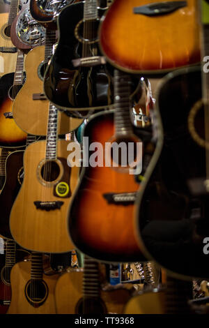 metal string acoustic guitars hanging on the walls of music store ready to perform Stock Photo