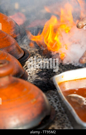 cooking in traditional moroccan tajine pot over open fire Stock Photo