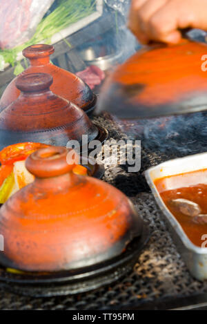 cooking in traditional moroccan tajine pot over open fire Stock Photo