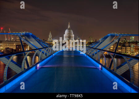 View across the Millennium Bridge to St Paul's Cathedral, lit with blue lighting. Long exposure at night, London. Stock Photo