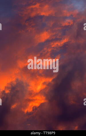Sunset cloudscape showing grey clouds and colours from the sun which is below the horizon. Stock Photo