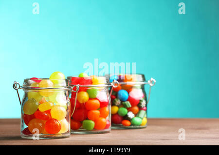 Colorful candies in jars on table on blue background Stock Photo