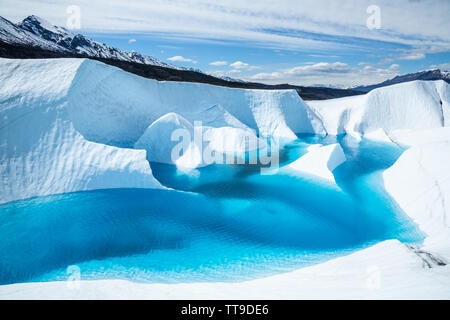Crystal blue waters of a supraglacial lake on the Matanuska Glacier fills in narrow canyons and fins of ice, or seracs, jut out from the deep blue wat Stock Photo