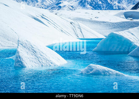 Ice cut from the melting glacier sticking out of crystal blue water on the Matanuska Glacier. Stock Photo