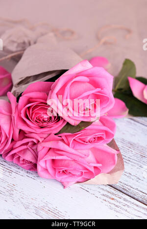 Beautiful pink roses on wooden table with parchment, closeup Stock Photo