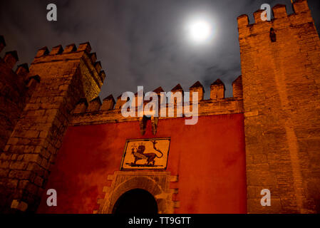 front gate of moorish fortress alcazar in sevilla, andalusia, spain, by night with cloudy sky and full moon Stock Photo