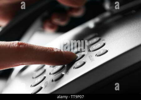Finger pressing number button on telephone to make a call, close up Stock Photo