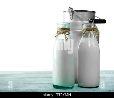 Retro can for milk and glass bottles of milk on wooden table, on white background Stock Photo