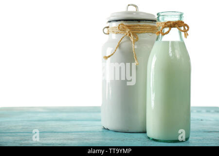 Retro can for milk and glass bottle of milk on wooden table, on white background Stock Photo