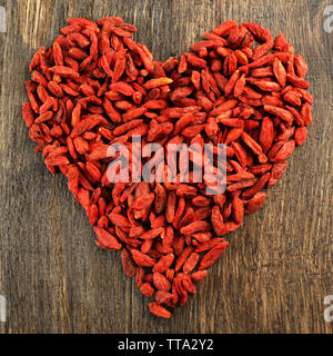 Goji berries arranged in heart shape on wooden background Stock Photo