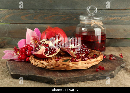 Pomegranate seeds on wicker tray and jar of juice on wooden background Stock Photo