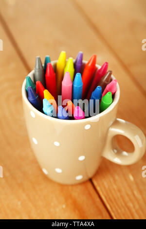Colorful pastel crayons in cup on wooden background Stock Photo