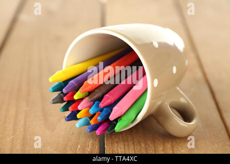 Colorful pastel crayons in cup on wooden background Stock Photo