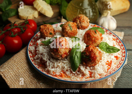 Meat balls in tomato sauce with boiled rice and lentil, wooden spoon on wooden background Stock Photo