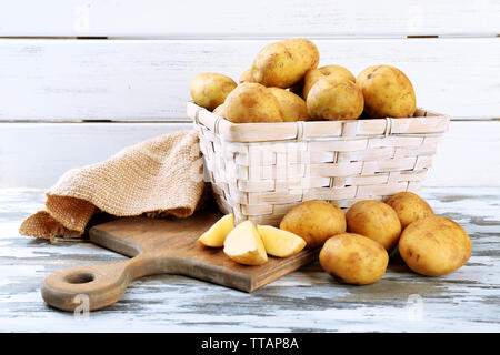 Young potatoes in wicker basket on wooden background Stock Photo