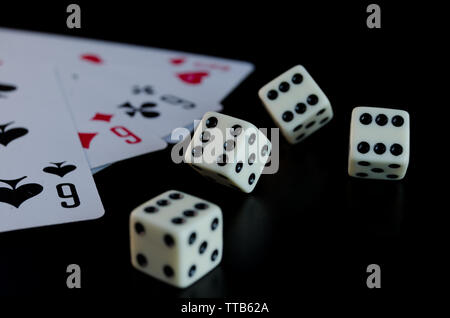 Dice, playing cards on a black background thrown on the table Stock Photo