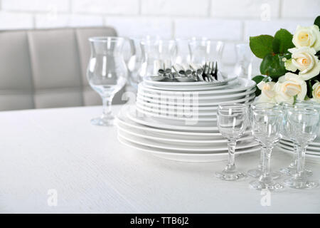 Clean plates, glasses and cutlery on white table Stock Photo