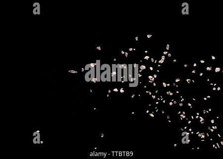 Split debris of stone exploding against black background. Stock Photo