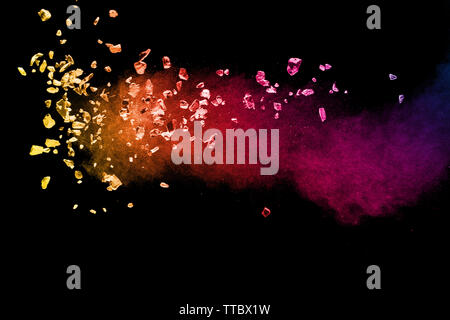 Split debris of colored stone with dust exploding against black background. Stock Photo