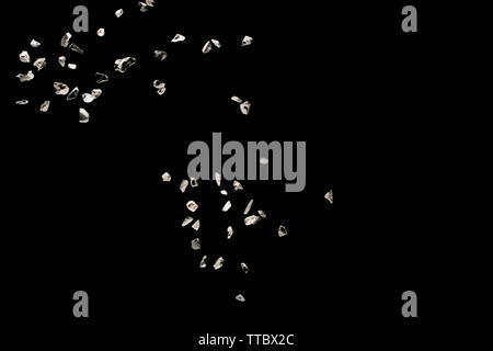 Split debris of stone exploding against black background. Stock Photo