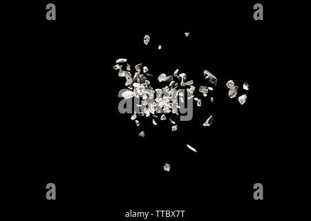 Split debris of stone exploding against black background. Stock Photo