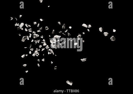 Split debris of stone exploding against black background. Stock Photo