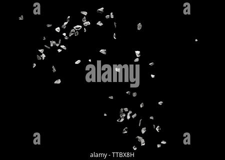 Split debris of stone exploding against black background. Stock Photo