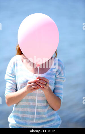 Girl holding balloon near face Stock Photo