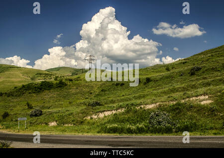 The highway among the mountains of Geghama mountain range near the village of Voghjaberd in Armenia on the background of blue sky, covered by a huge C