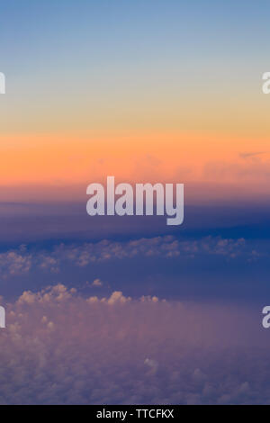 Beautiful sunset sky above clouds with dramatic light. Cabin view from airplane Stock Photo