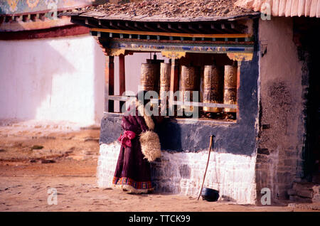 Tibetan woman in traditional clothing spinning prayer wheels,Palcho Chode monastery,Gyantse,Tibet Stock Photo