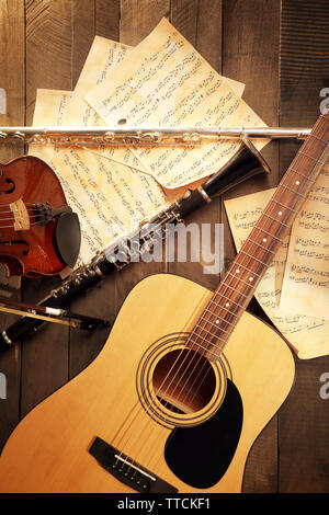 Acoustic guitar, soprano saxophone, violin, flute and note sheets on wooden background Stock Photo