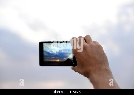 Man using smart phone for taking photo of beautiful sky Stock Photo