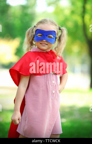 Superhero little girl plays at the park Stock Photo