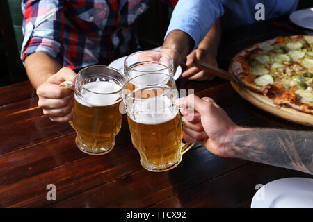 Male hands holding glasses with beer Stock Photo