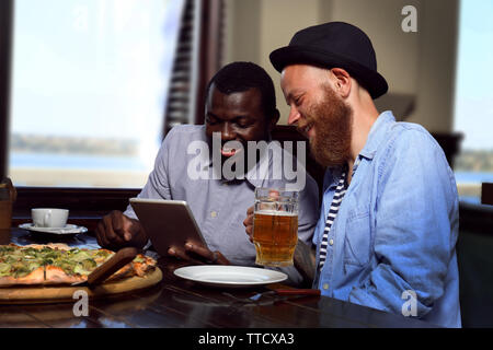 Young men drinking beer and talking in cafe Stock Photo