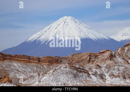 Valle de la Luna (Valley of the Moon) with the snowy Licancabur volcano in the background, the white in the foreground is salt, Atacama Desert, Chile Stock Photo