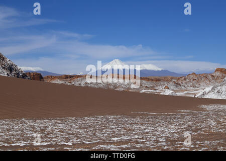 Valle de la Luna (Valley of the Moon) with the snowy Licancabur volcano in the background, the white in the foreground is salt, Atacama Desert, Chile Stock Photo