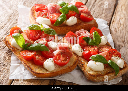 Italian open sandwiches with mozzarella, tomatoes, ham and basil closeup on the table. horizontal Stock Photo