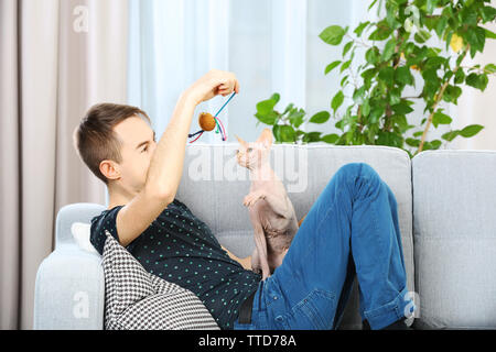 Young handsome man sitting with cat on couch at home Stock Photo