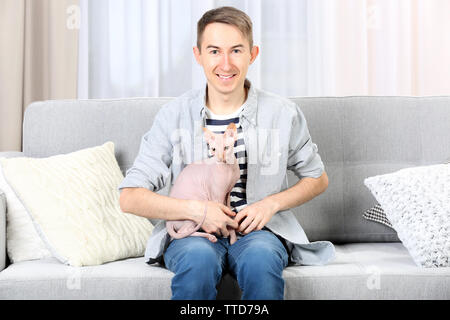 Young handsome man sitting with cat on couch at home Stock Photo