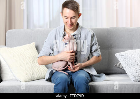 Young handsome man sitting with cat on couch at home Stock Photo