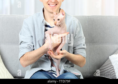 Young handsome man sitting with cat on couch at home Stock Photo